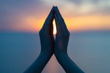 Women's hands in the blue purple sunset as a symbol of yoga or religion, namaste silhouette - obrazy, fototapety, plakaty