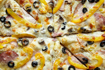 Pizza with chesse, ham, yellow bell pepper, olives and mushrooms background closeup