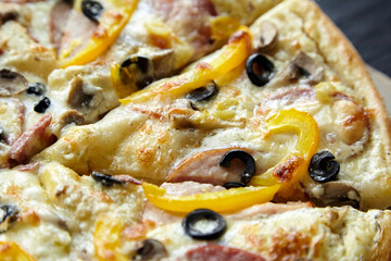 Pizza slices with chesse, ham, yellow bell pepper, olives and mushrooms, background , closeup