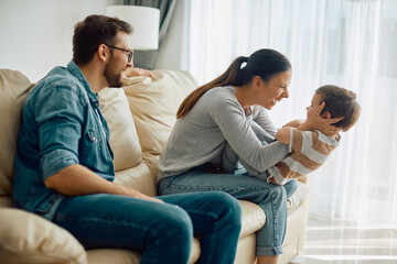 Happy parents having fun with their small son at home.