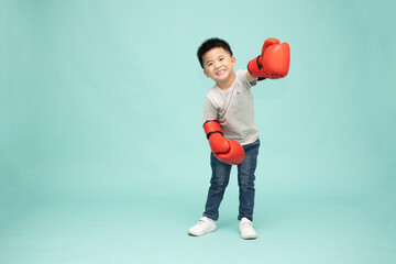 Little Cute Asian boy with red boxing gloves isolated on green background, Fighter concept, 3 years old
