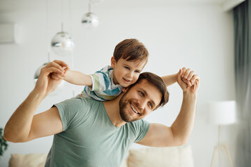 Happy father having fun while playing with his small son at home. - obrazy, fototapety, plakaty