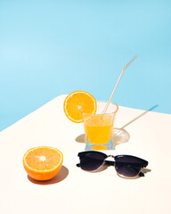Summer composition with yellow orange juice on the table with sunglasses. Sunny summer day.