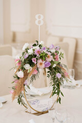 Centerpiece made of green leaves and fresh flowers stands on the dinner table. Wedding day. Fresh flowers decorations.
