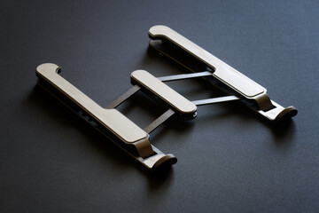 Foldable portable laptop stand with silicone overlays on a dark background.