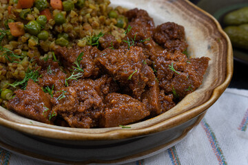 Vegan buckwheat and vegetables with seitan on plate, dark table, copy space