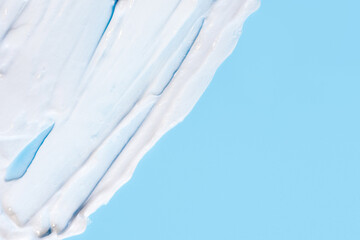 The texture of the skin or hair care product. White smears of cream, mask or balm on a blue background.