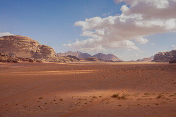 red desert of wadi rum with car tracks in the sand, cloudy weather, beautiful contrasting shadows,...