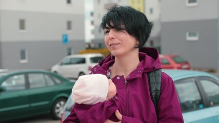A young mother is caring for a baby with sling jacket. Clothing design for attachment parenting. The close bond between parent and child during conscious motherhood.