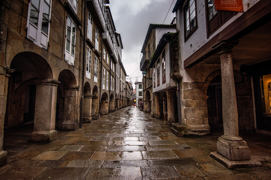 Fototapeta Santiago de Compostela - October 2018: Narrow street with porticoes in Santiago de Compostela on a rainy day