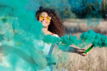 Beautiful young woman hold light up colored smoke bombs - Happy friends having fun in the park with...