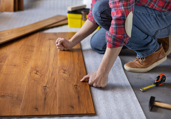 Man worker installing laminate flooring. Wooden laminate floor plank and tools - 432897801