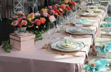 Table set up for bridal shower on bright summer day with flowers and vintage tea cups on each plate