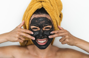 Young woman applying charcoal mask on face - Happy girl having skin care spa day at home - Healthy beauty clean treatment and youth people lifestyle concept