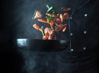 Naklejka premium Professional chef prepares shrimp with herbs. Cooking seafood, healthy vegetarian food and food on a dark background