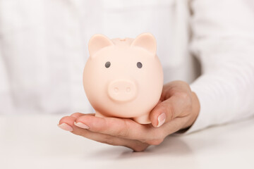 Obraz na płótnie Canvas Piggy bank in hand on light background, space for text. Finance, saving money. Business to success and saving for retirement concept