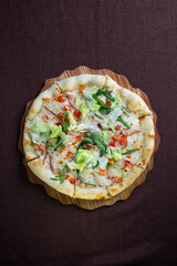 pizza with meat and lettuce on a wooden stand top view