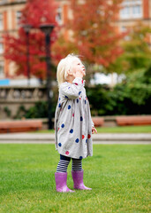 Fototapeta premium portrait of a little girl in grey dress fooling and walking around in city