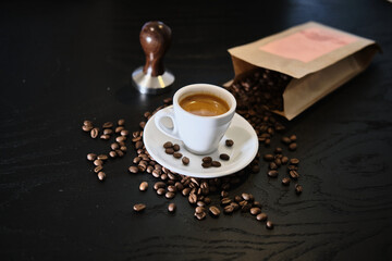 coffee beans on table with tamper and cup of espresso