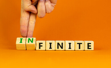 Finite or infinite symbol. Businessman turns wooden cubes and changes the word 'finite' to 'infinite'. Beautiful orange table, orange background. Business, finite or infinite concept. Copy space.