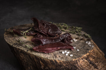 Dried deer meat on the sawn-off tree. Local food.Selective focus - obrazy, fototapety, plakaty