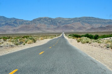 Lonely desert road to the mountains of Inyo County California on a clear beautiful afternoon.