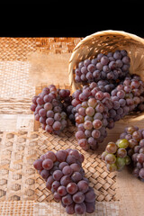 Grapes, overturned basket with grapes falling on the table, selective focus.