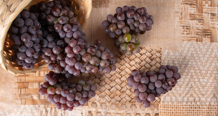 Grapes, overturned basket with grapes falling on the table, top view.