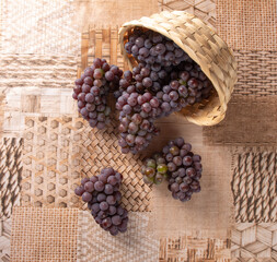 Grapes, overturned basket with grapes falling on the table, top view.