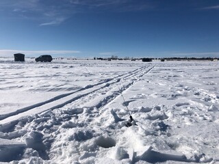 Fototapeta na wymiar Ice fishing on a frozen lake in Alberta, Canada. The frozen lake covered with white snow in the middle of the winter