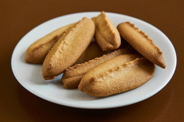 Fototapeta na wymiar Baked cookies on white plate on brown background.