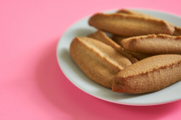 Baked cookies on white plate on pink background.
