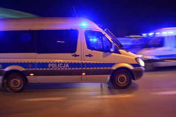 Specjalistyczny samochód policji polskiej w akcji nocnej pod stadionem piłki nożnej. 