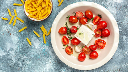 baked feta pasta. cooking recipe ingredients, oven baked cherry tomatoes and feta cheese with olive oil and thyme. Trending viral recipe. Top view