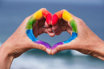 hands in the shape of heart. Rainbow painted on hands