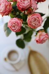 Cup of coffee for breakfast on a gold tray and a bouquet of pink roses