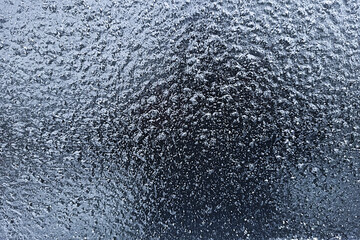 Frozen drops of water on glass. Freezing rain. Abstract background, ice on glass.