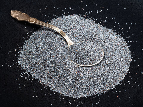 tablespoon in pile of poppy seeds on black plate