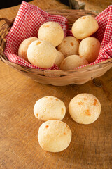 Brazilian cheese bread, basket with checkered cloth with cheese breads on rustic wood, selective focus.