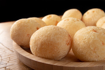 Brazilian Cheese bread, cheese breads arranged on wooden plate, on rustic wood, selective focus.
