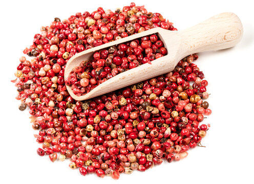 scoop on pile of pink peppercorns on white