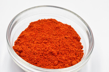 Spice sweet dried red paprika pepper powder closeup against white