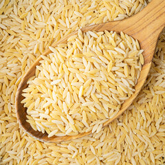 uncooked risoni pastina in wooden spoon closeup