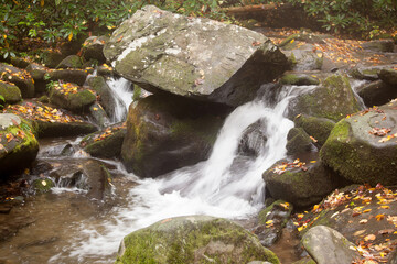Naklejka na ściany i meble Cascading stream outdoors with rocks