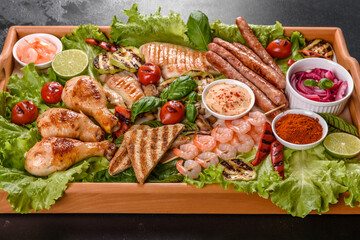 Composition of sausages, chicken, pork and shrimp prepared on grill, as well as vegetables prepared on grill with spices and herbs