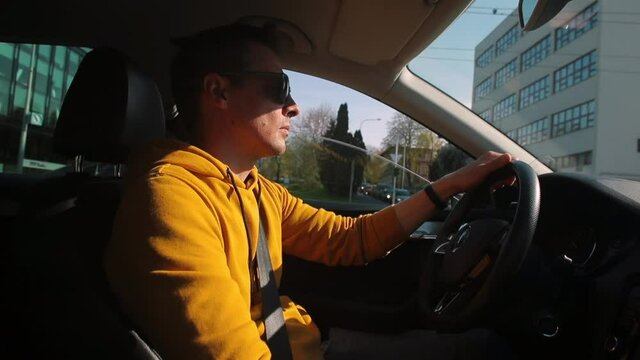 A man starts driving a car at an intersection in the city. He puts down the phone, makes a start. The focus of attention is vehicle management.