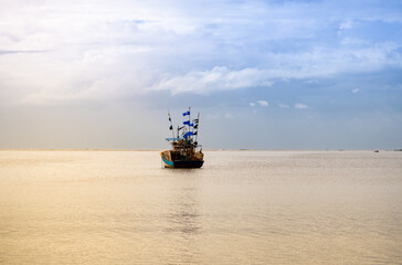 Fototapeta premium Fishing boat in the ocean under the sunlight. Clouds in the sky.