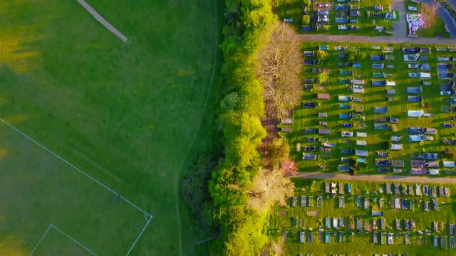 Bird eye view down a line of trees bisecting a cemetery and basketball court