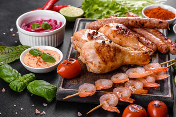 Composition of sausages, chicken, pork and shrimp prepared on grill, as well as vegetables prepared on grill with spices and herbs