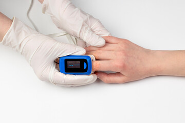 Doctor hand in white medical latex gloves hold patients hand with pulse oximetry on the finger. Noninvasive and painless oxygen saturation level test. Part of set.